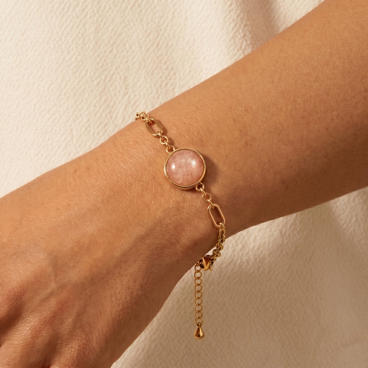 Cora sunstone bracelet on the wrist, gold chain and glowing orange sunstone gemstone detail