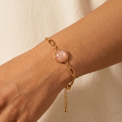 Cora sunstone bracelet on the wrist, gold chain and glowing orange sunstone gemstone detail
